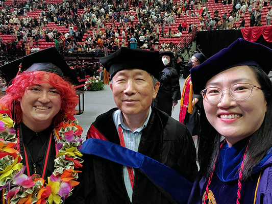 student and two faculty at commencement